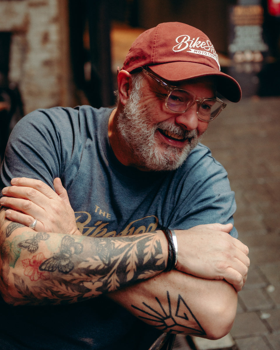 Model wearing Bike Shed Moto Script cap red sitting on brick driveway