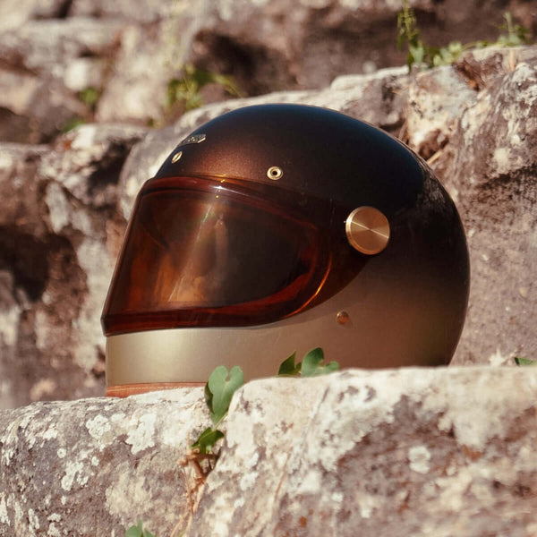 Brown motorcycle helmet on a stone wall with a natural background