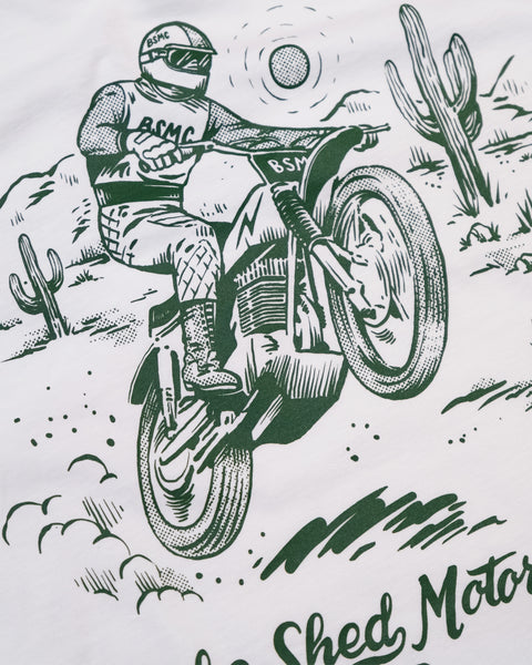 Illustration of a person riding a motorcycle in a desert landscape with cacti. Graphic screen print Bike Shed Moto Co t-shirt