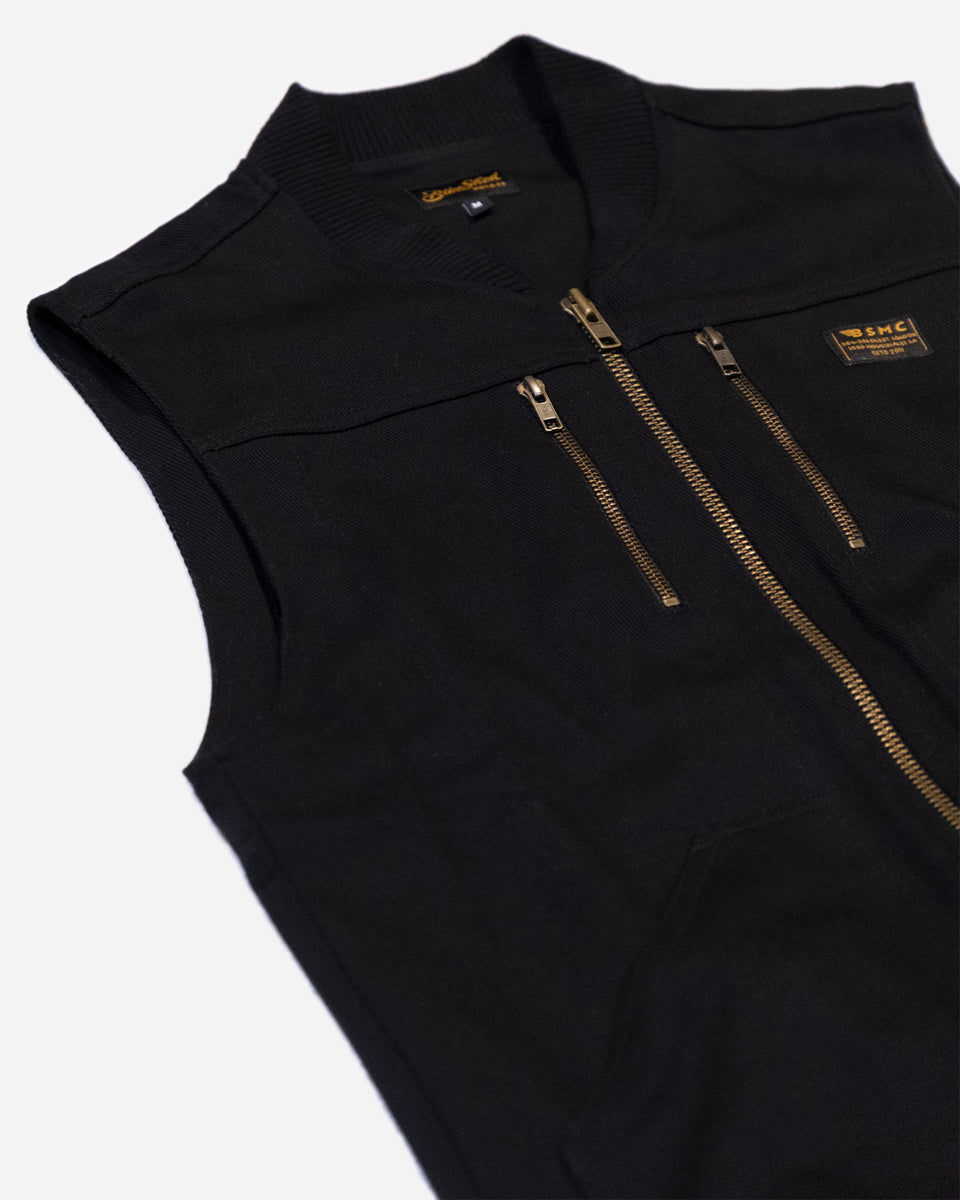 Black motorcycle vest with gold zippers with a Bike Shed Moto Co logo on a white background
